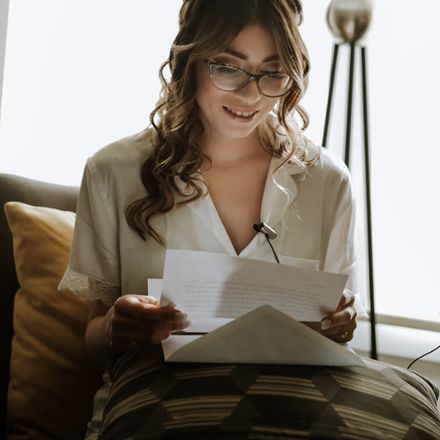 Une femme lit une lettre sur un canapé